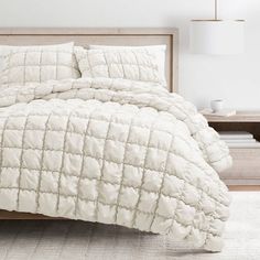 a bed with white comforter and pillows in a room