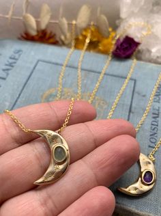 "This listing is for one gold necklace. It features a tarnish resistant 14k gold plated chain that you can pick the length of at check out. The gold crescent moon features laser engraving in delicate star burst designs, and has a faceted semi-precious stone within the moon. You can pick from lapis lazuli, amethyst, or aventurine. Check out my other listings for other necklaces, as well as earrings, pins, rings, and more. Your earrings will be wrapped in bubble wrap, protectively sealed in a hand Moon Shaped Brass Necklace For Gift, Moon-shaped Brass Necklace For Gift, Amethyst Moon Charm For Jewelry Making, Celestial Amethyst Moon Charm Jewelry, Celestial Amethyst Jewelry With Moon Charm, Moon Phase Oval Necklace For Gifts, Mystical Gold Charm Necklace Gift, Oval Moon Phase Necklace As A Gift, Brass Moon Charm Necklace For Gift