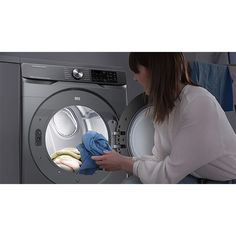 a woman is looking at her clothes in the washing machine