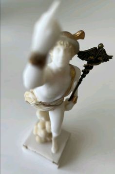 a white figurine with an angel holding a stick on it's back