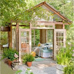 a garden shed with lots of potted plants and flowers in the front yard area