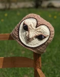 a crocheted owl hat sitting on top of a wooden chair