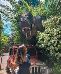 a woman standing in front of a fake dinosaur head on the back of a truck