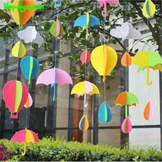 colorful paper umbrellas hanging from the side of a tree in front of a building