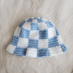 a crocheted blue and white hat laying on top of a bed