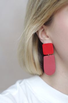 This is a pair of eye-catching statement earrings in a simple, geometric design- the top square is a bright cherry red color and the bottom rounded shape is a faded, dusty red color. These earrings have a minimalist design that is timeless, while the bright duo-tone colors add a modern vibe. These earrings are crafted using polymer clay, a surprisingly lightweight material that won't weigh you down. Each earring is carefully sanded and smoothed to ensure a well-made piece of jewelry that is comf Red Jewelry With Matching Earrings For Everyday, Trendy Red Drop Earrings, Red Everyday Earrings, Modern Red Jewelry For Everyday, Modern Red Everyday Jewelry, Trendy Red Jewelry With Matching Earrings, Trendy Red Jewelry Set With Matching Earrings, Modern Handmade Rectangular Earrings, Trendy Square Earrings As Gift