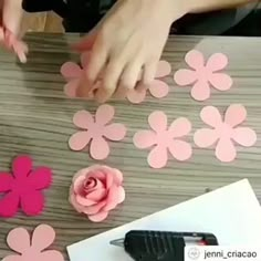 someone cutting out paper flowers on a table