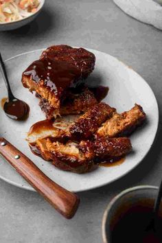 ribs covered in bbq sauce on a white plate with chopsticks next to it