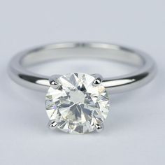 a round cut diamond ring on a plain surface with the center setting in white gold