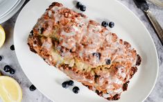 a white plate topped with blueberry scones next to sliced lemons and silverware