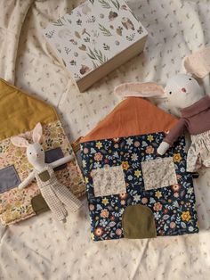 two stuffed animals laying on top of a bed next to quilts and fabric blocks