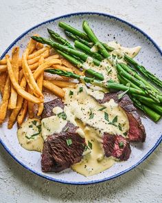 steak, asparagus and french fries on a plate with gravy sauce