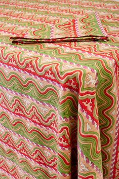 an image of a colorful table cloth on top of a wooden table with red, green and white designs