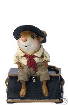 a toy mouse with a hat and tie sitting on top of a luggage bag in front of a white background