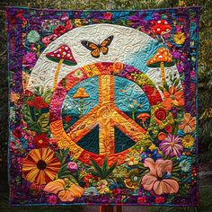 a peace sign quilt hanging on a wooden pole in front of some trees and flowers