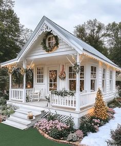 a small white house with christmas decorations on the porch