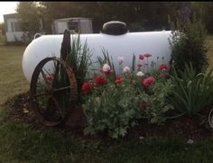 an old propane tank is surrounded by flowers and plants