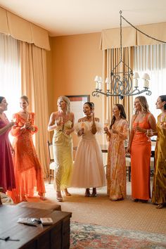 a group of women standing next to each other in front of a chandelier