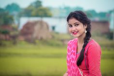 a young woman in a pink top is smiling at the camera and has her hands on her hips