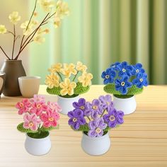 four small vases with flowers in them on a table