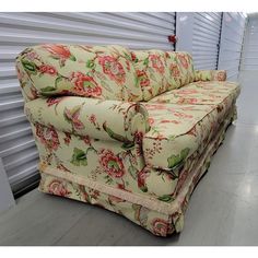 a floral couch sitting on top of a hard wood floor next to a garage door