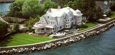 an aerial view of a large white house on the edge of a body of water