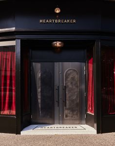 an entrance to a building with red curtains on the outside and black doors that say heartbeatbreakerer