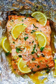 salmon on foil with lemons and parsley garnished in seasoning, ready to be cooked