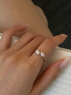 a close up of a person's hand holding an open book with a ring on it