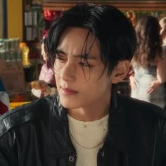 a man with black hair wearing a leather jacket