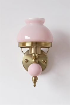 a pink and gold light fixture on a white wall