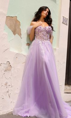 a woman in a purple dress leaning against a wall