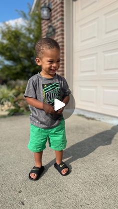 a little boy standing in front of a garage