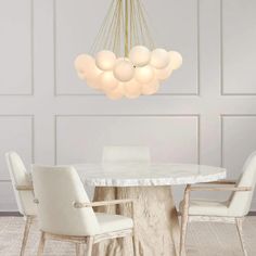 a dining room table with white chairs and a chandelier hanging from the ceiling