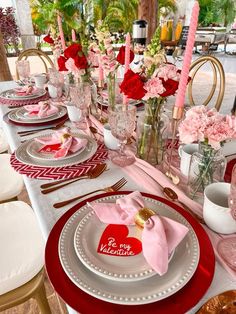 a table set for valentine's day with pink and red flowers