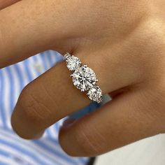 a woman's hand with a three stone diamond ring on her left finger,