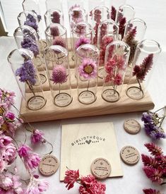 a table topped with lots of glass vases filled with pink and purple flowers on top of