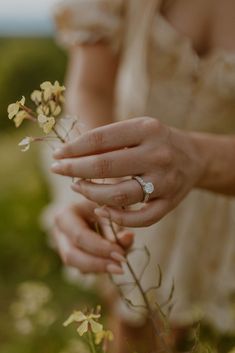 a close up of a person's hand holding flowers in their left hand and wearing a wedding ring