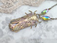 a necklace with a bug on it sitting on top of a lace covered tablecloth