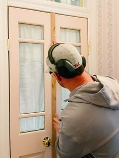 a man wearing headphones is opening the door to his house and looking at it