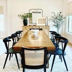 a dining room table with black chairs and a white rug on the floor in front of it