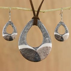 three pairs of earrings hanging from a tree branch on a brown string with a wooden background