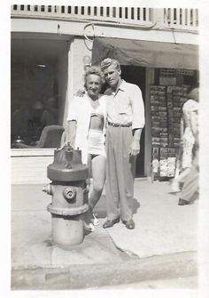 an old black and white photo of two people standing next to a fire hydrant