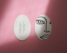 two paper plates with faces on them against a pink background