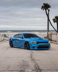 a blue dodge charger parked on the side of the road next to the ocean