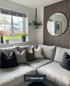 a living room filled with lots of furniture next to a wall mounted mirror and potted plants