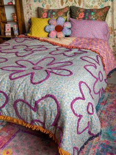 a bed with colorful bedspread and pillows on top of it in a bedroom