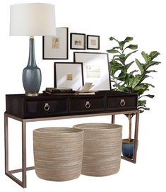 a console table with two large round baskets underneath it and framed pictures on the wall