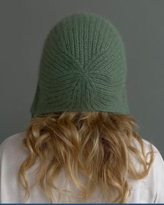 a woman with long blonde hair wearing a green knitted hat over her head and back