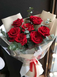 a bouquet of red roses wrapped in white paper